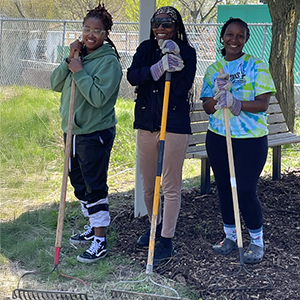 Students pose with gardening tools.